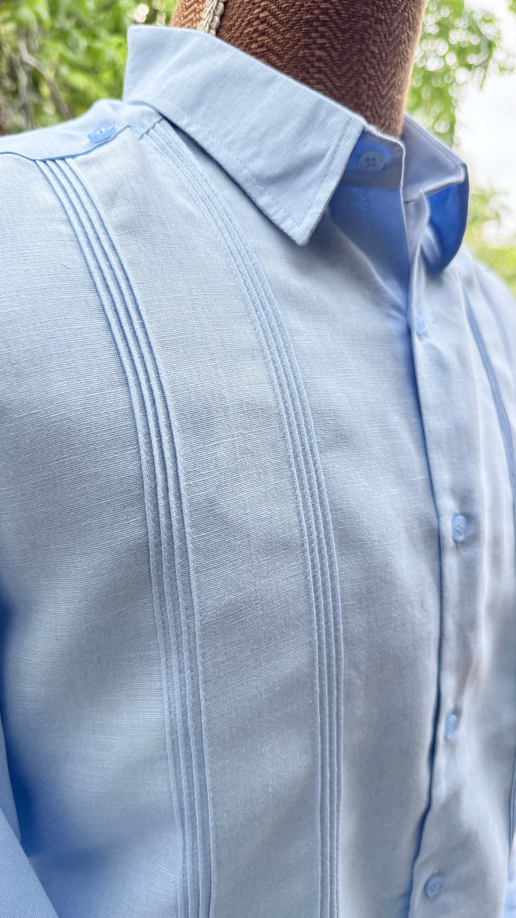 Detalle del bordado artesanal de la guayabera de lino azul de Herlinda Flores, hecha a mano en México.