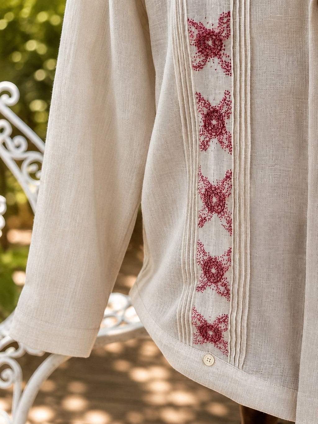 Herlinda Flores beige linen guayabera shirt with vertical pleats and intricate red floral embroidery.
