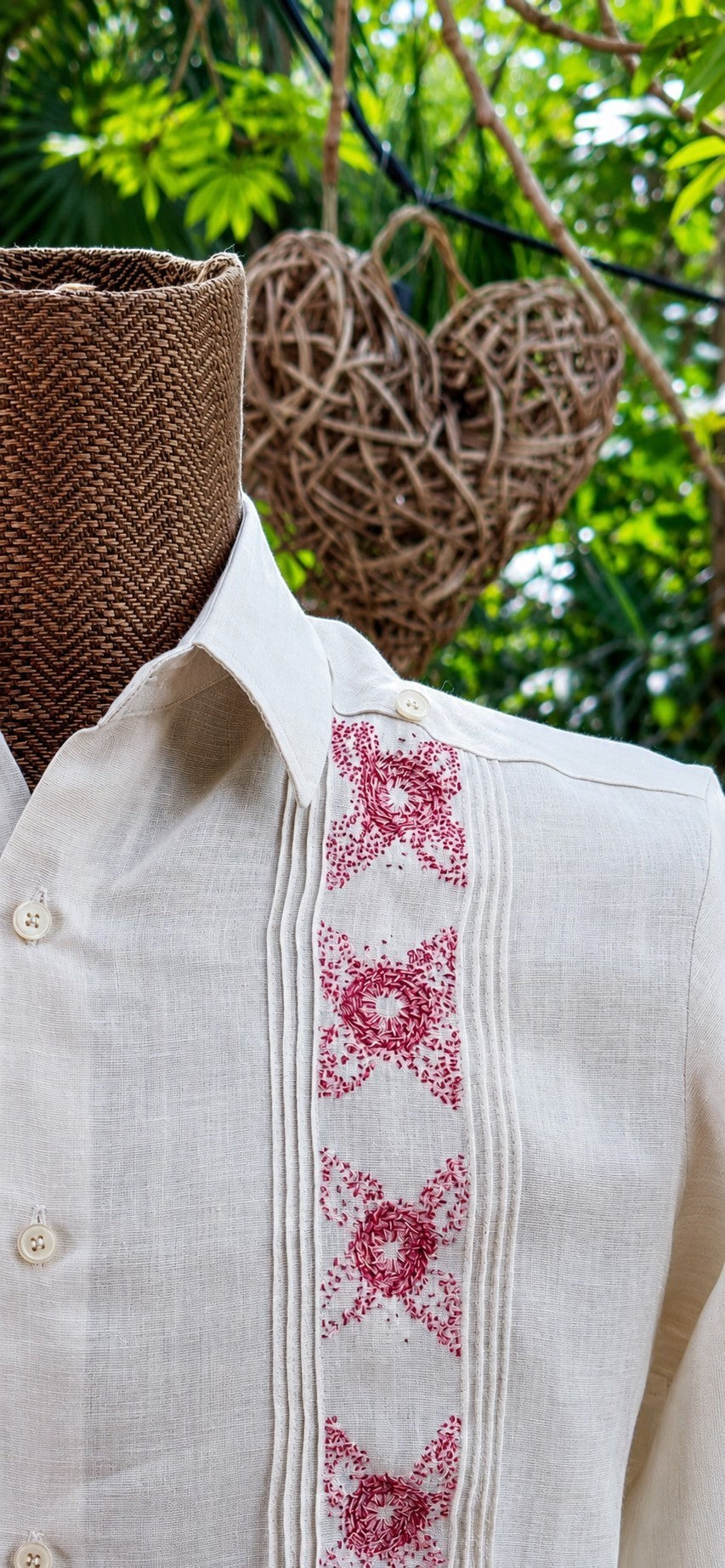 Herlinda Flores beige linen guayabera shirt with red floral embroidery and vertical pleats on a mannequin.